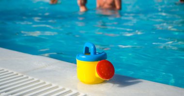 Child's watering-can at the pool clipart