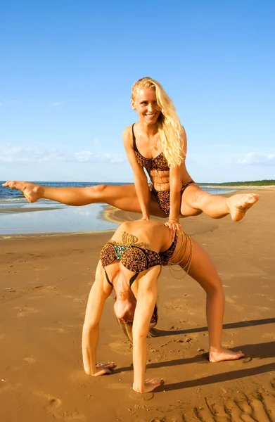 ビーチでの 2 つのアクロバティックな女の子 — ストック写真