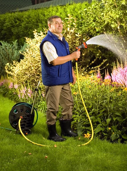 Мужчина поливает цветы в саду — стоковое фото