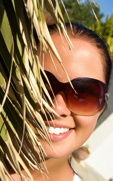 Vacker ung kvinna bakom palm — Stockfoto