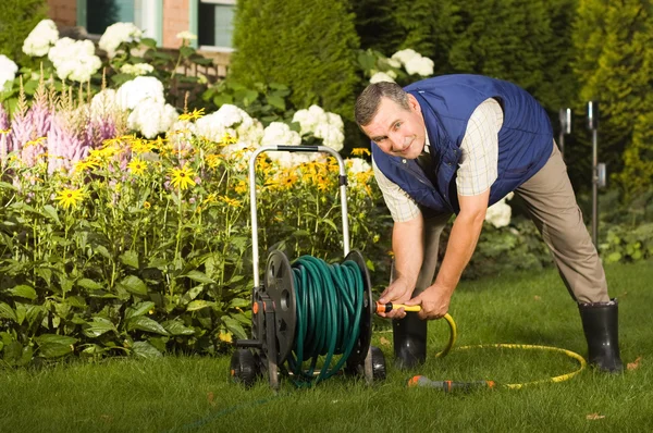Человек чистит шланг в саду — стоковое фото