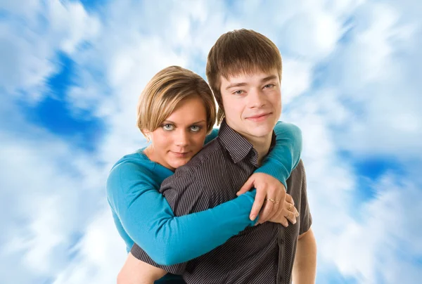 Jong (echt) paar knuffelen (blauwe hemelachtergrond) — Stockfoto