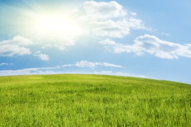 Green hill under blue cloudy sky clipart