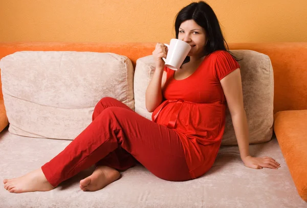 Ciężarna kobieta siedzi na kanapie — Zdjęcie stockowe