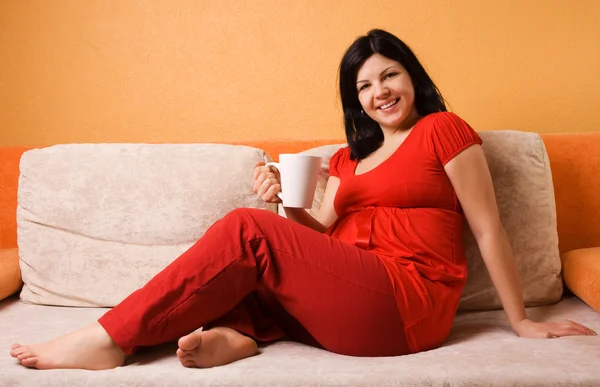 Mujer embarazada sentada en el sofá —  Fotos de Stock