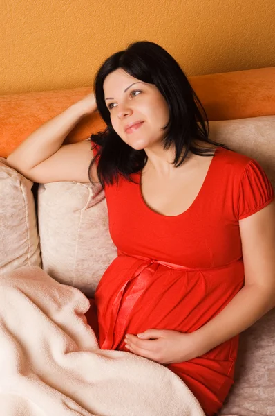 Hamile kadın kanepede oturan — Stok fotoğraf