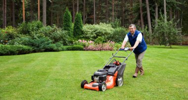 Senior man mowing the lawn. clipart