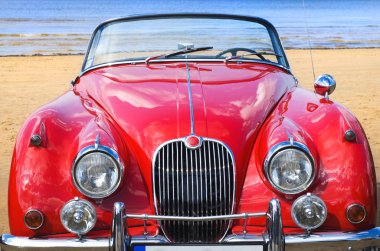 Old classic red car at the beach clipart