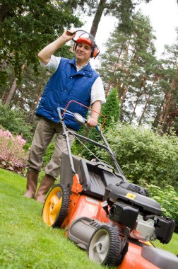 Senior man mowing the lawn. clipart