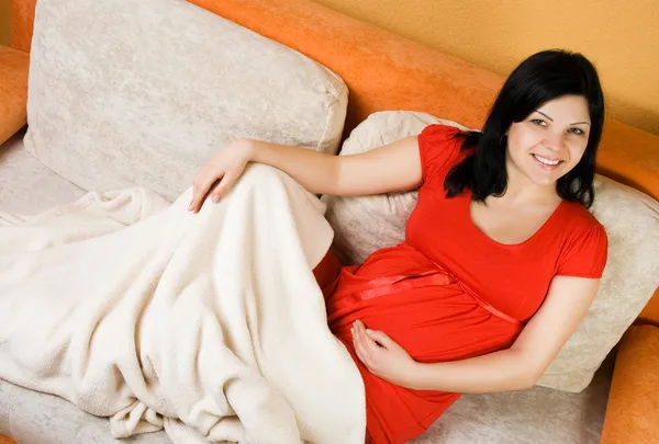 Femme enceinte assise sur le canapé — Photo