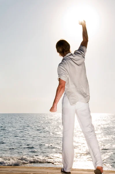 Человек на пляже поднимает руку — стоковое фото