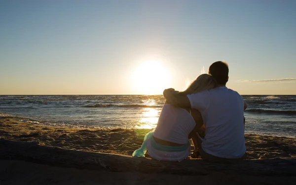 Couple sitting near the sea on sunset