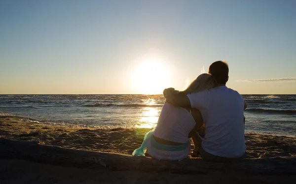 Couple sitting near the sea on sunset