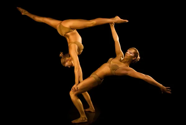 Twee acrobatische meisje afgezwakt in goud — Stockfoto