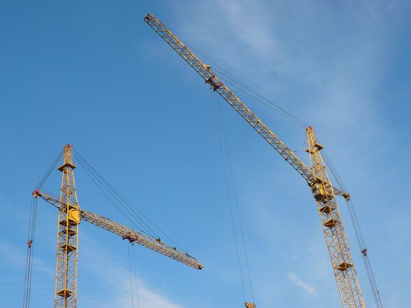 Two crane towers on sky background at day