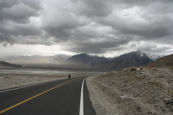 Osamocený cyklista na prázdných horské silnici — Stock fotografie