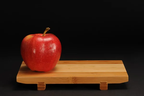 Червоне яблуко на дерев'яній підставці. — стокове фото