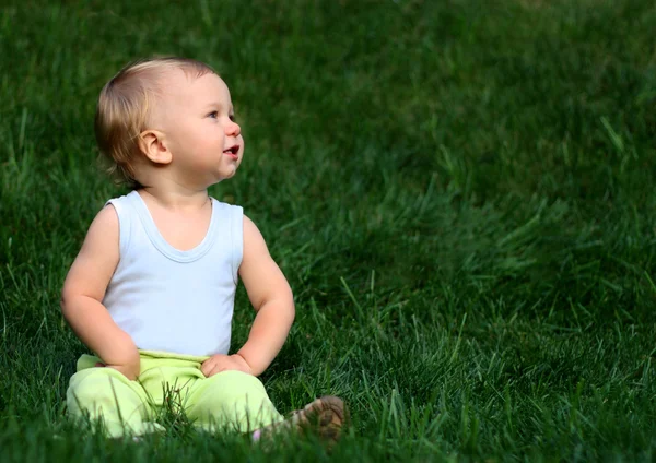 Chlapec sedí na trávě — Stock fotografie