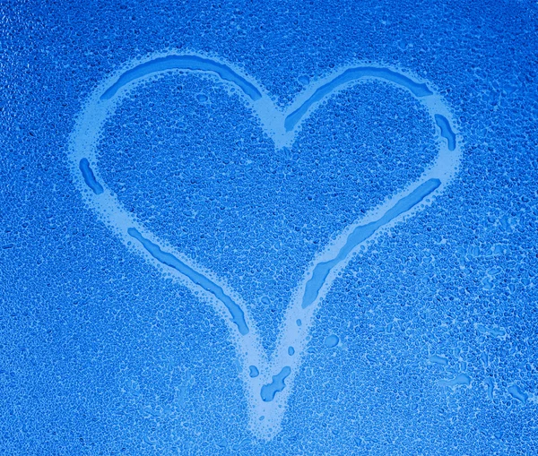 Srdce podepsat na mokrém skle v modrém tónu — Stock fotografie