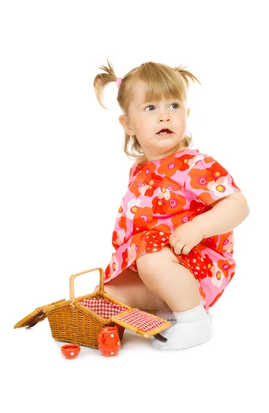 Bebê pequeno em vestido vermelho com cesta de brinquedo — Fotografia de Stock