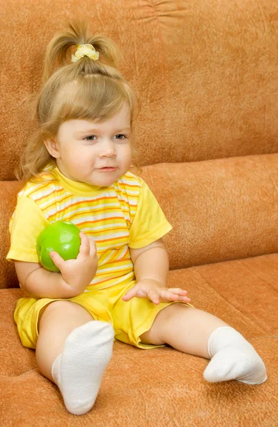 Маленька дівчинка в жовтому їсть зелене яблуко — стокове фото