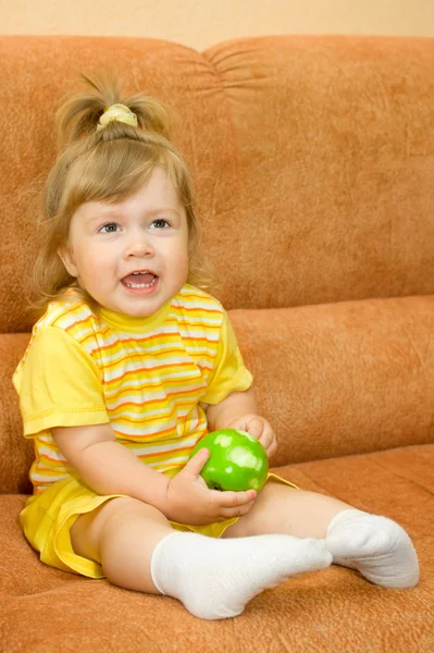 Маленькая девочка в желтом есть зеленое яблоко — стоковое фото