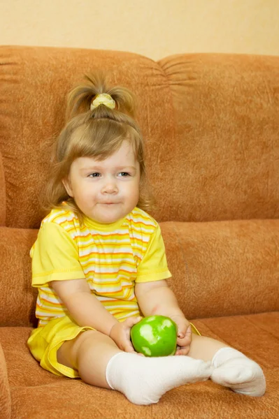 Little smiling girl in yellow eat apple — Stock Photo, Image