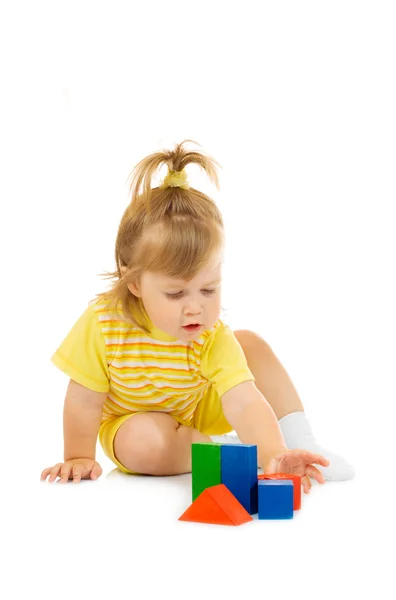 Маленькая девочка в желтом строит игрушечную пирамиду — стоковое фото