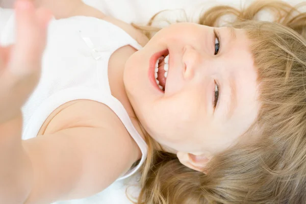 Lachende meisje in een bed — Stockfoto