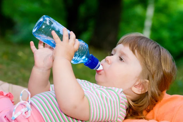 Klein meisje drinkt water uit een fles — Stockfoto