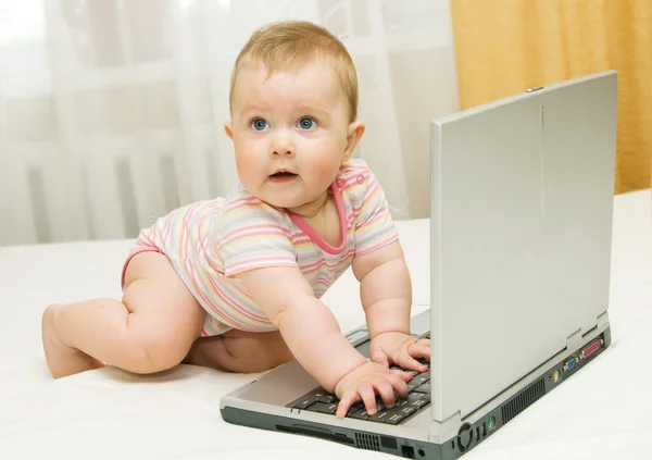 Petit bébé et ordinateur portable sur le lit — Photo
