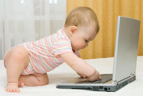 Small baby and laptop on bed — Stock Photo, Image