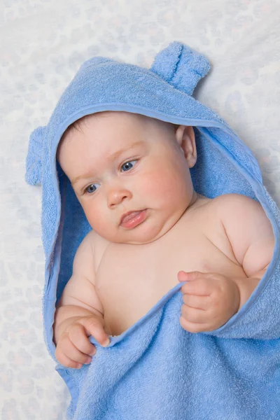 Kleines lächelndes Baby in blauem Handtuch — Stockfoto