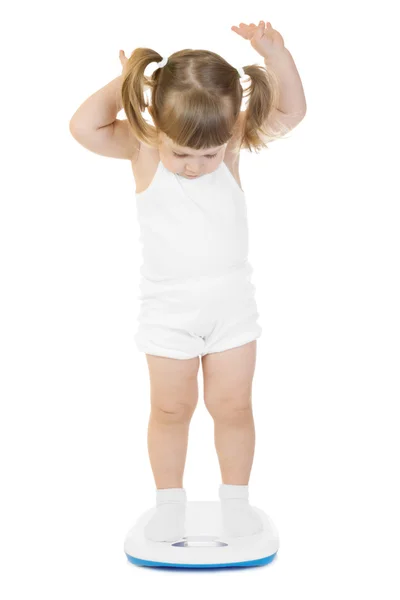 Маленька смішна дівчинка стоїть на вагах — стокове фото