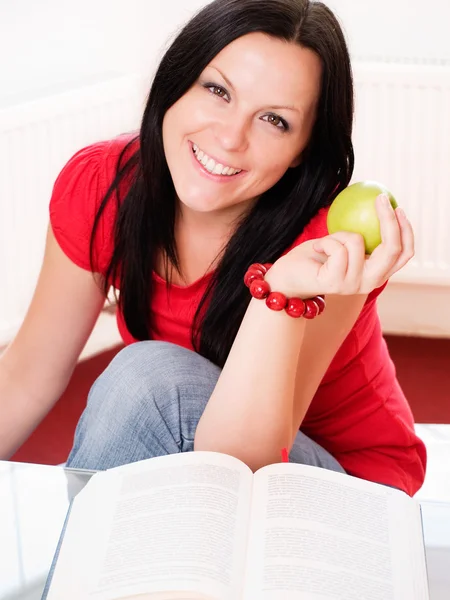 Mujer morena sonriente sosteniendo una manzana — Foto de Stock