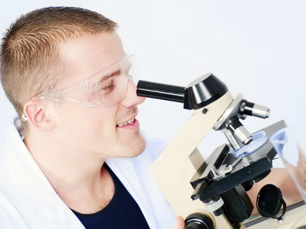 Усміхнений чоловік досліджує мікроскоп — стокове фото