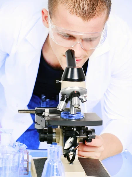 Hombre sonriente investigando en un microscopio —  Fotos de Stock