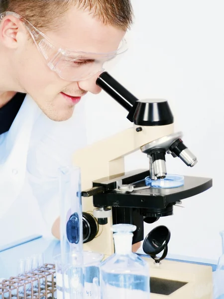 Усміхнений чоловік досліджує мікроскоп — стокове фото