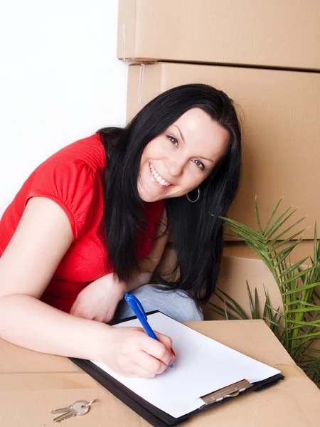 Woman with package signs delivery paper — Stock Photo, Image