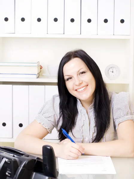 Посміхаючись брюнетка жінка працює в офісі — стокове фото