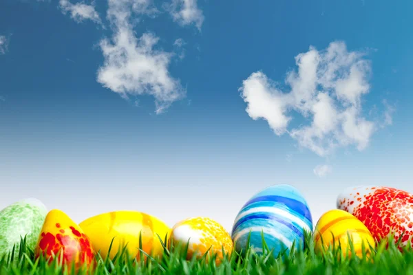 Easter eggs in green grass over blue sky with cl — Stock Photo, Image