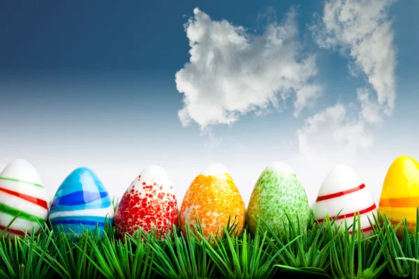 Huevos de Pascua en hierba verde sobre el cielo azul con cl —  Fotos de Stock