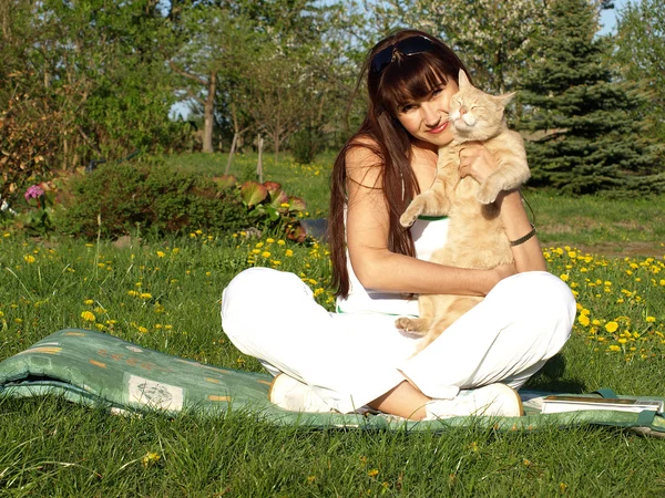 Krásná brunetka v parku s kočkou — Stock fotografie