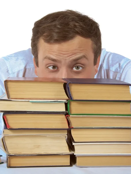 Homem olha para uma pilha de livros — Fotografia de Stock
