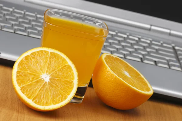 Апельсини, сік і ноутбук . — стокове фото