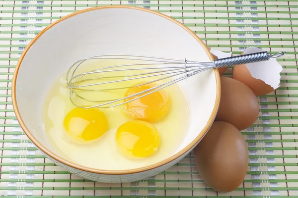 Eggs and whisk. — Stock Photo, Image
