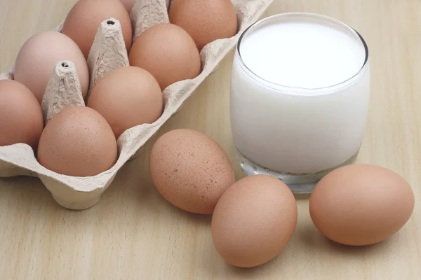 Huevos y leche sobre mesa de madera —  Fotos de Stock