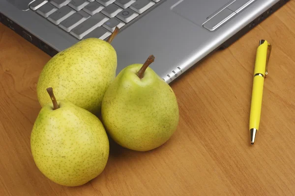 Päron och laptop på träbord — Stockfoto