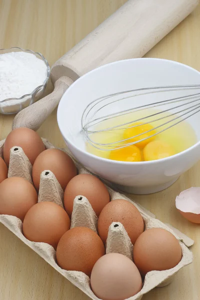 Jaja i mąka na drewnianym stole — Zdjęcie stockowe