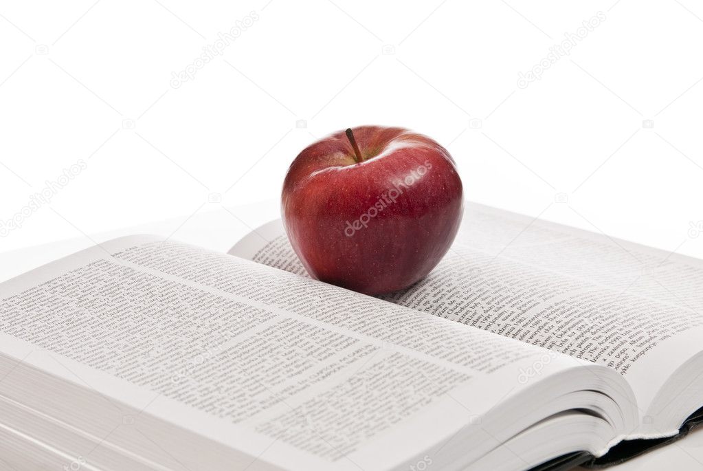 Opened hefty book and fresh red apple